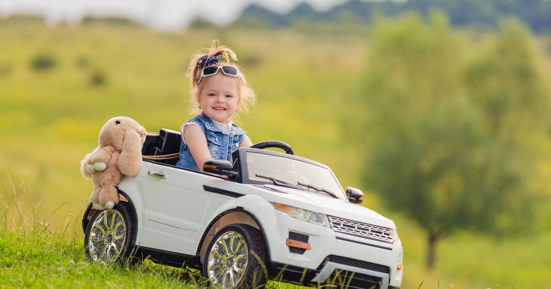 A little girl wearing a denim vest and sunglasses while driving over grass in an electric ride-on car with one seat.