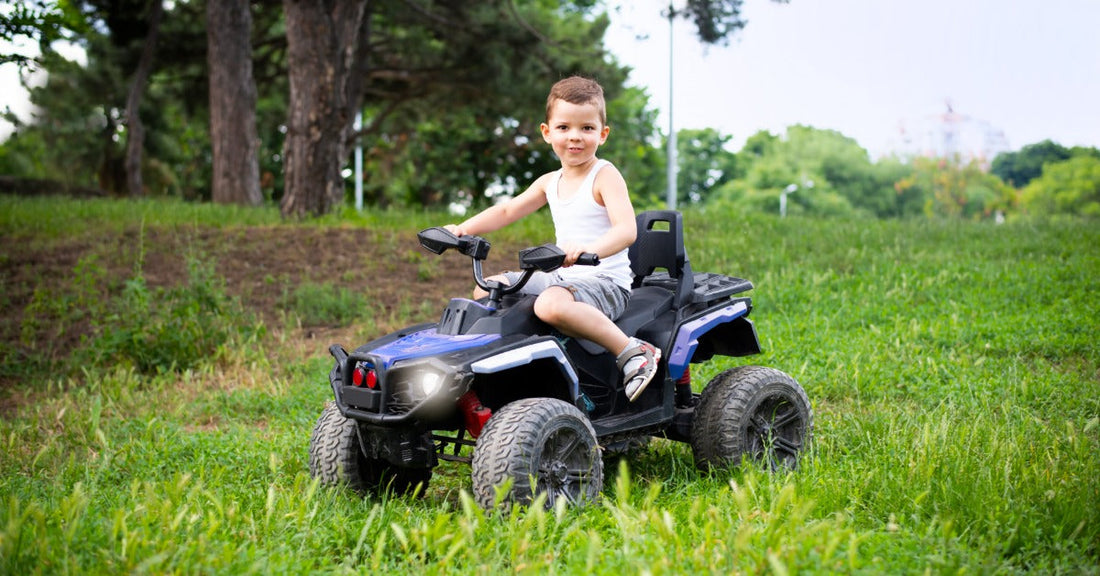 A young boy sitting on a blue and black electric ATV in the middle of an open field with trees in the background.