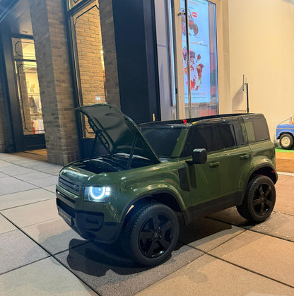 An olive green toy car modeled after a Land Rover Defender, featuring an open hood and black wheels